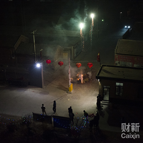除夕夜，小区门口的年轻人在燃放烟花。比起小时候，现在放烟花的已经少多了。但这个习俗仍被固执的保留下来，否则没点烟花爆竹感觉年将不年。近年来在家乡一种非常不好的风气开始蔓延，有些家庭为了炫耀财力，动辄花费上万买上一车的烟花，就为了过年时“弄点动静”出来。烟火在天际沸腾，地上一片狼藉，清洁工大爷挥舞着扫帚，嘴里念念有词。 杜广磊/财新记者