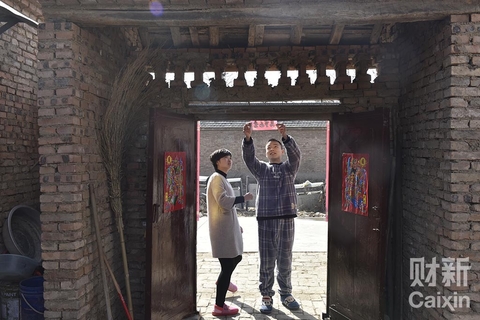 除夕那天，丁森和女友在家贴春联，以前是他父亲在家张罗，今天父亲出门办事，交给丁森，小伙子第一次自己张罗，发现讲究很多。比如什么对联要贴大门口，什么适合贴堂屋，贴的高度和位置，对联的上联和下联，门神是对脸还是不对脸，是先放鞭炮还是后放鞭炮。 陈亮/财新记者