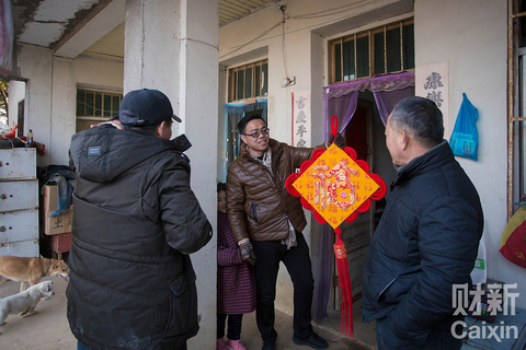表哥提溜着自己从上海带回来的福挂，向姑父请示摆在哪里；被套上围裙帮忙的侄女忙里偷闲过来凑热闹，因为没怎么见过这两位亲戚，她紧紧拉着爸爸的手，躲在他身后。 陈玮曦/财新记者