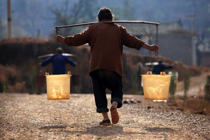 2012年2月22日,云南宜良,84岁的陈吉英老人担着两桶水往家里赶.