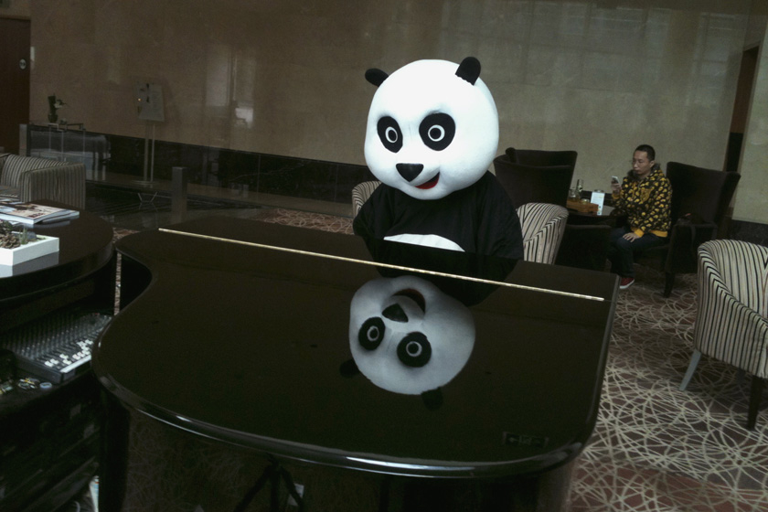 2012年3月18日，北京，在一家酒店的商业活动上，一名扮成熊猫的女子在看一架钢琴。 REUTERS/Jason Lee_财新每周图片(2012.3.17-3.23) 