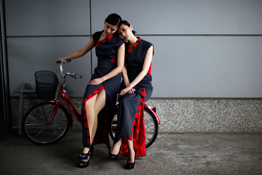 4月15日，上海，2012 F1大奖赛上海站期间，两位举牌的女孩在起跑位置休息。 Carlos Barria/REUTERS_财新每周图片(2012.4.14-4.20) 