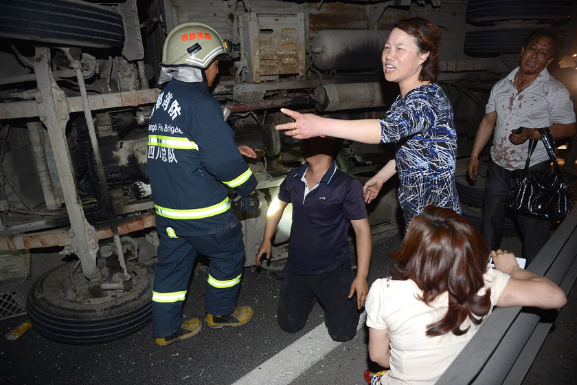2012年4月25日，四川省成都市绕城高速，死者的儿子跪在地上哀求消防救他母亲。当日，在绕城高速上发生一起车祸造成1人死亡，一人受伤。 成都商报/CFP_财新每周图片(2012.4.21-4.27) 