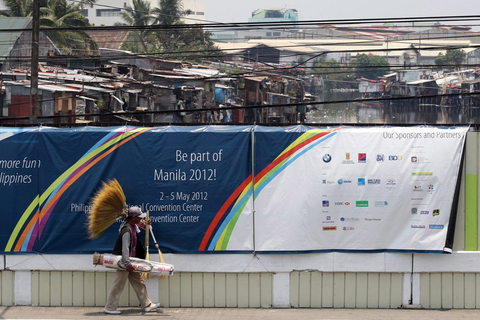 5月3日，菲律宾马尼拉，行人经过遭海报覆盖的墙壁，背后是大片的贫民窟。 CFP