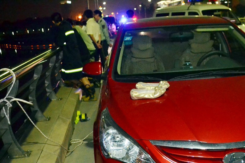 5月6日，江苏扬州，桥面上停放的跳湖者的红色轿车，车引擎盖上留有一双女式鞋子。 徐海风 孟德龙/东方IC_扬州一局长携女子跳湖身亡