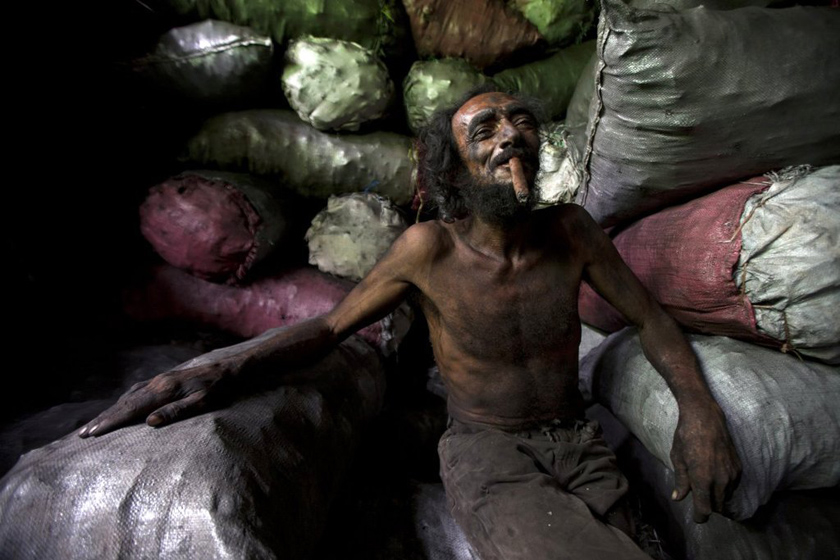 2012年5月8日，尼加拉瓜首都马那瓜，Israel Lewites市场的煤袋搬运工塞乔在休息时抽雪茄。 Nicolas Garcia/东方IC_财新每周图片(2012.5.5-5.11) 