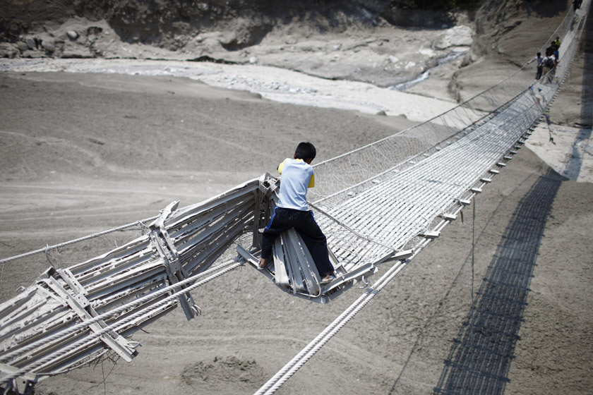 2012年5月6日，尼泊尔卡斯基地区，一个男孩在山洪暴发后试图通过一座受损的吊桥。 REUTERS/Navesh Chitrakar_财新每周图片(2012.5.5-5.11) 
