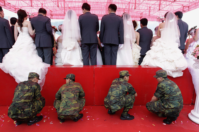 2012年5月10日，在台北举行的一场部队集体婚礼上，新婚夫妇站在一个台子上拍集体照，数名士兵蹲在后面以防台子倒塌。约264对夫妇在婚礼中喜结良缘。 REUTERS/Pichi Chuang_财新每周图片(2012.5.5-5.11) 