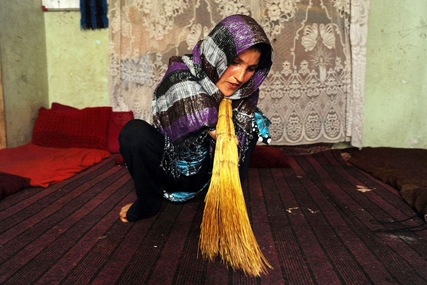 2012年5月9日，阿富汗赫拉特，33岁的帕丽正在打扫屋子。帕丽年幼时，她的村庄在苏联出兵阿富汗的战争中被炸，帕丽也因此失去双手。现在她靠制作和销售工艺品养活她的孩子和上了年纪的丈夫。 Aref Karimi/东方IC_财新每周图片(2012.5.5-5.11) 