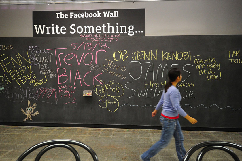 5月15日，Facebook的一名员工从一面“脸书墙”旁边走过。公司员工可以在黑板上涂写各种内容。 ROBYN BECK/东方IC_探访Facebook新总部