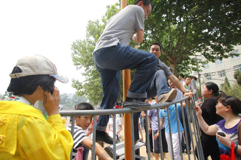 5月20日，济南外国语学校考场，焦急的家长翻越栏杆进入操场。 依旧/东方IC_济南外国语学校“小升初”近万人赴考