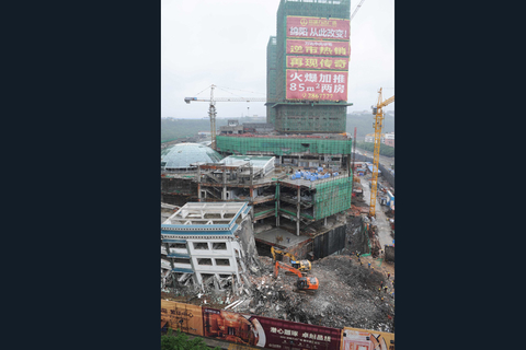 5月21日，工程机械在拆除绵阳紫荆民族中学校舍，旁边则是建设中的万达广场。 李桥桥/新华社