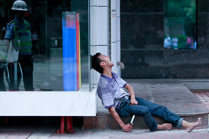 5月24日上午，广东佛山，疑似吸毒者手持尖刀，腰部别一把菜刀，边打电话边大声嚎叫自残。  郭继江/CFP_佛山警方用钢叉制伏“双刀男”