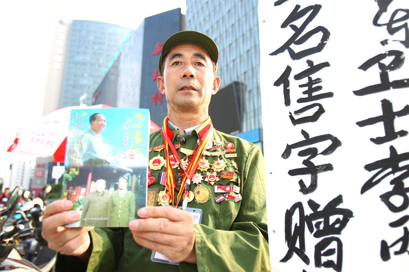 7月5日，毛泽东生前警卫李丙需顶着烈日端坐在郑州市街头，签名赠书。 王琪/东方IC_毛泽东警卫街头“摆摊”赠书