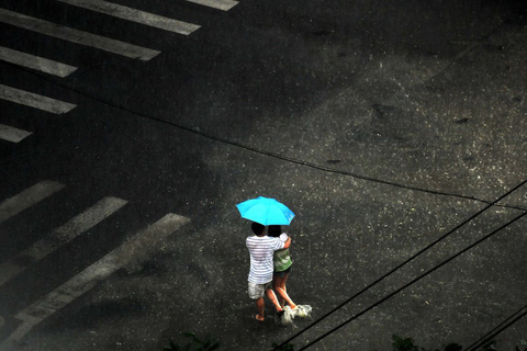 7月10日傍晚，北京突降暴雨，两名行人互相搀扶淌着水在雨中前行。 王苡萱/CFP