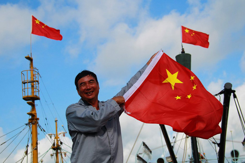 7月12日，海南三亚，琼三亚72029的卢师傅挥舞着国旗。每次出海捕鱼他都会带上两面崭新的国旗。 霍立渤/CFP_海南最大规模渔船队抵达南沙永暑礁 