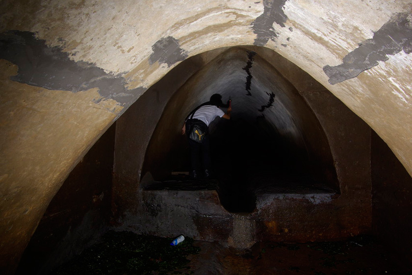 2010年6月4日，青岛，下水道内的环境很差，没有灯光，记者除了用闪光灯偶尔看看前方，就只有依靠蜡烛。  李隽辉/CFP_探秘青岛百年德建排水系统