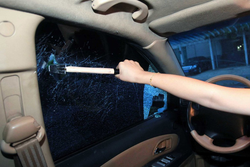7月23日，北京，一位女士用锤子尝试砸车窗角部砸4次将车窗砸碎。 新京报王贵彬/CFP_图解车内破窗逃生方法
