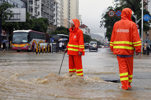 7月25日，深圳，水务工人打开窨井盖排水，并站在旁边看护。 周游/CFP