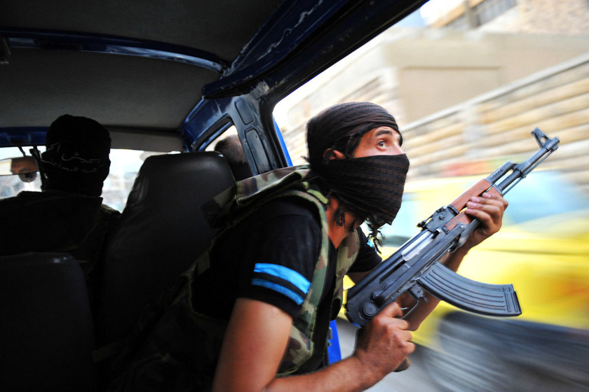 2012年7月23日，叙利亚Selehattin，一名反政府军士兵在袭击当地政府大楼的战斗中寻找狙击手。 BULENT KILIC/东方IC_财新每周图片(2012.7.21-7.27)