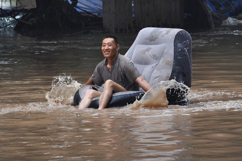 2012年7月25日，洪峰逐渐退去，在重庆长滨公园路段，漂浮在水中的沙发被一位市民当成皮划艇。 renjun/东方IC_财新每周图片(2012.7.21-7.27)