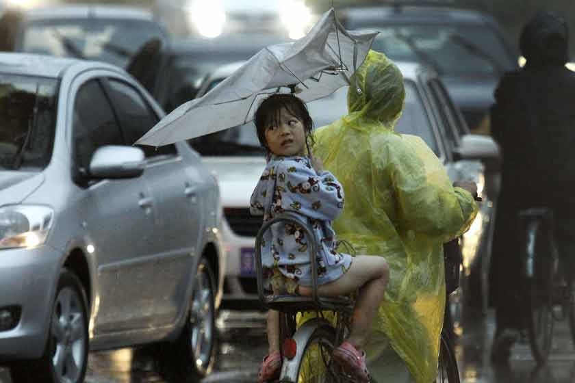 2012年7月21日，在风雨中向后张望的小女孩。 CFP_北京逝者