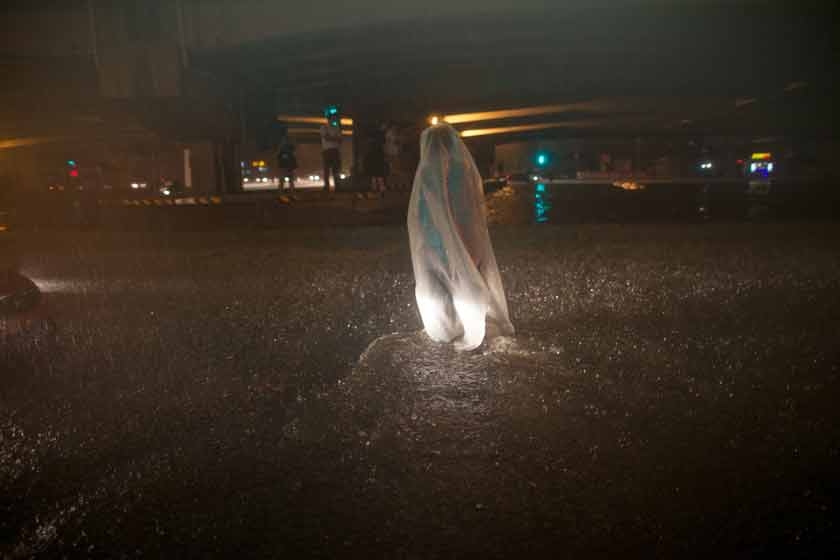 2012年7月21日，刘家窑桥底严重积水。一位市民裹着一个白色的袋子遮雨。周岗峰/CFP_北京逝者