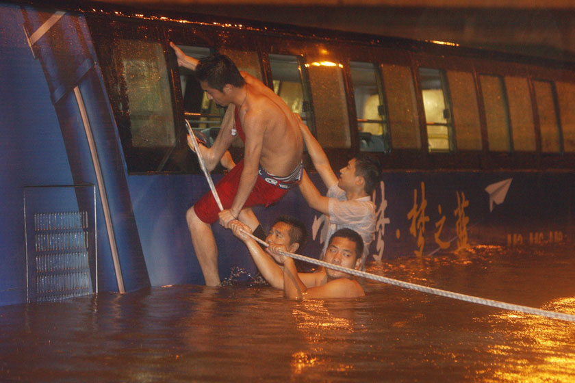 2012年7月21日，消防队员和志愿者在营救被困乘客。 万象/新华社_北京逝者