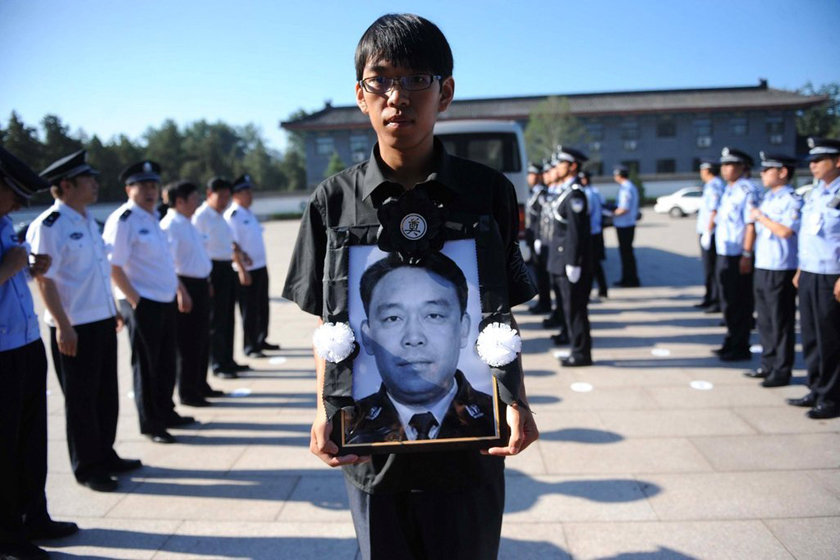 7月29日晨，在八宝山殡仪馆，李方洪的儿子捧着父亲的遗像。  东方IC_北京万人送别暴雨中殉职派出所所长