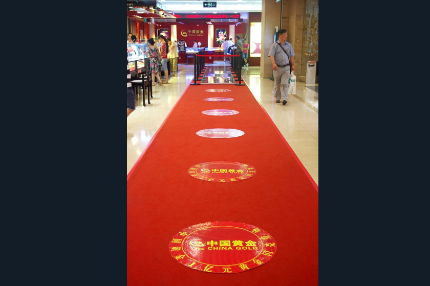 8月5日，武汉，世贸广场珠宝节现场，铺设在中国黄金专柜前的“金光大道”。 陈文/东方IC_商家用200公斤金砖铺“金光大道”