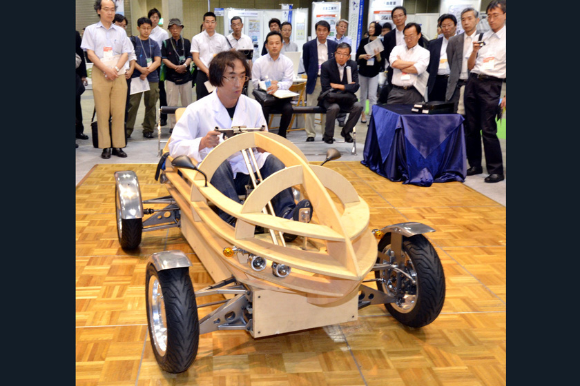 在日本东京举行的汽车工业博览会上，日本电动汽车俱乐部的成员给观众展示组装完成的木制单人电动车。    东方IC_盘点潮爆新能源汽车