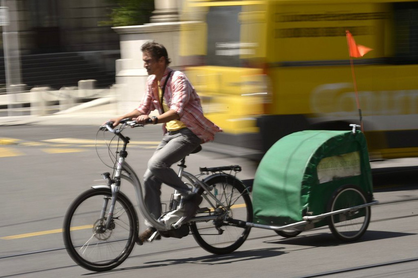 一名男子骑着电动车自行车，车身后还拖着一个小货车。    东方IC_盘点潮爆新能源汽车