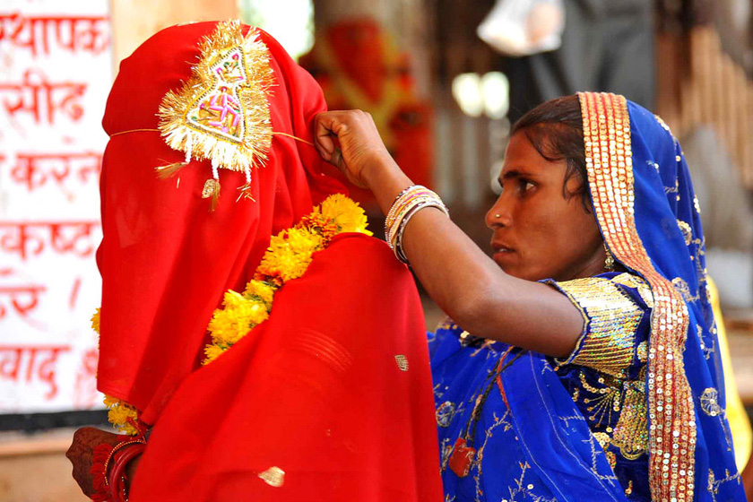 当地时间2011年5月7日，印度拉贾斯坦邦Kamkheda村，一名妇女为15岁的女儿Sintu整理新娘的头纱。   Prakash Hatvalne/东方IC_揭秘印度童婚陋习 娃娃新娘3岁出嫁