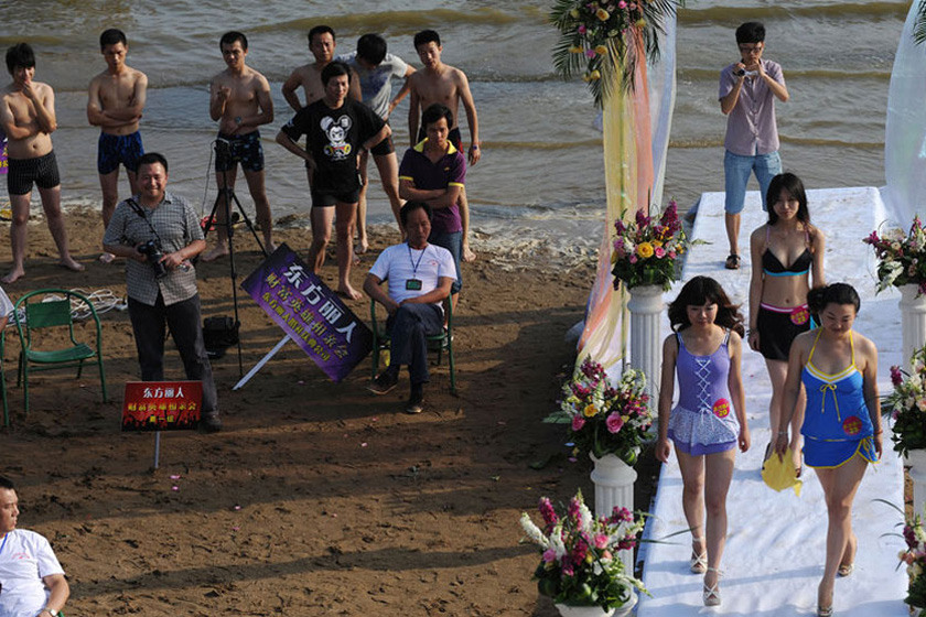 2011年6月25日，在武汉东湖沙滩浴场举行的财富英雄相亲会现场，女子身穿比基尼展示自己。    陈亮/CFP_“中国式”富豪相亲