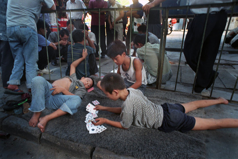 2000年5月23日，广东深圳，几个流浪孩子在街头打牌消磨时间。他们每天在同样的时间同样的地点出现，偶尔会和一些成年盲流在一起，打牌是消磨时间的好办法。   高见/CFP