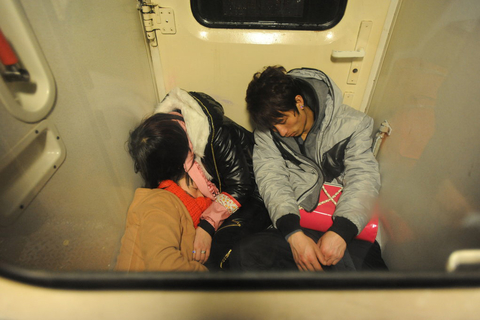 很多火车的开车时间是第二天清晨，由于只能提前4小时进入候车厅，不少旅客早早来到“临时候车厅”小睡一会儿。有的盖着自带的被子，有的在脚上套着塑料袋，有的干脆直接躺在冰凉的地面上。在火车上，没买到座票的旅客，找个能靠的地方就睡觉，不管安稳与否，只为心中的回家梦。图为2月1日，青岛至成都列车，在过道睡觉的旅客。   于滈/CFP