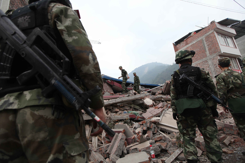 4月22日，宝兴县灵关镇，武警在一处倒塌的房子上寻找被埋群众。     牛光/财新记者
