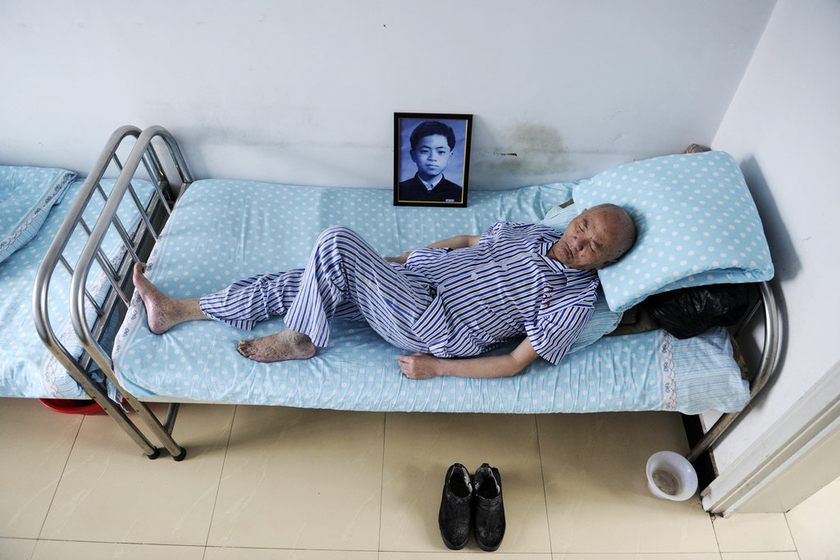 2013年7月4日，黑龙江佳木斯，在郜阿利床头，一张他16岁的照片日夜陪伴在他身边。枕头下，已经打包收拾后的行李一直搁着。“我明天就回上海，我儿子来接我”，然而第二天，郜阿利还是呆呆地坐在床沿，倔强地望着窗外。这名来自北京的知青，1964年来到852农场，是北京师范大学物理系的无线电专业一名学生。   孙俊彬/CFP_走不出的北大荒