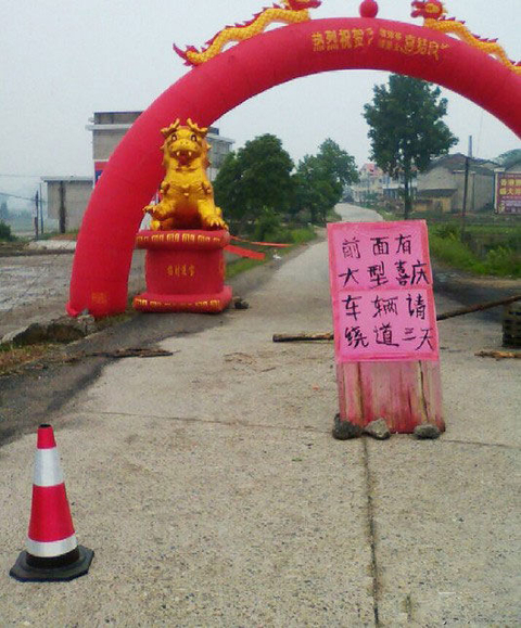 从“流沙河客”发的图片上看到，大型的红色充气拱门横跨公路两边，拱门下有一块提示牌，上写“前面有大型喜庆，车辆请绕道三天”，拱门下还有一些阻止车辆通行的障碍物。     图片来源网络