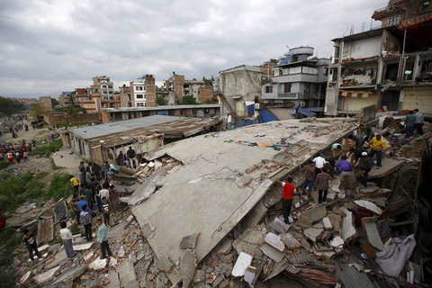 People gather near a collapsed house after a major earthquake in Kathmandu