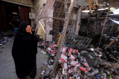 An Iraqi woman reacts as she stands amid the debris in the aftermath of a massive suicide car bomb attack carried out by the Islamic State group in the predominantly Shiite town of Khan Bani Saad