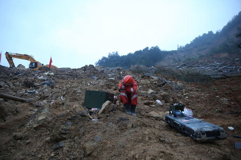 2015年11月15日，浙江丽水，救援人员连夜搜救失联人员。挖掘机在现场救援，疲惫的搜救人员坐在废墟上休息片刻。 浙报集团/东方IC