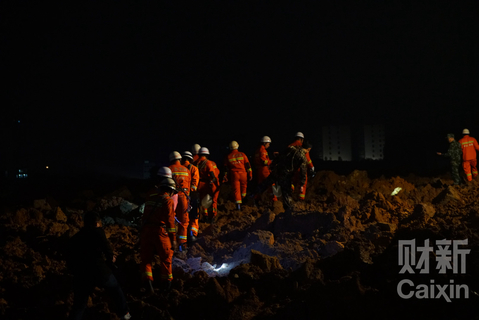20时许，救援人员连夜救援。这堆泥土下面埋着大约三四间厂房，泥土约有三层楼高，两辆挖掘机正在挖开泥土搜寻生还者。 梁莹菲/财新记者