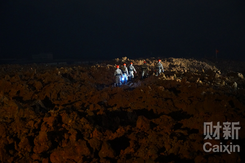 20时许，救援人员连夜救援。这堆泥土下面埋着大约三四间厂房，泥土约有三层楼高，两辆挖掘机正在挖开泥土搜寻生还者。 梁莹菲/财新记者