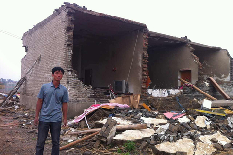 村民陈斯州站在损坏的房子前。 萧辉/财新记者