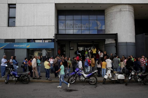 People line up to get into a Banco Mercantil branch in Caracas