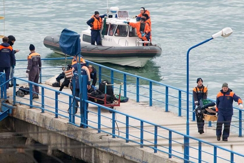 Russian rescuers carry a stretcher with passenger belongings after a Russian military plane crashed in the Black Sea
