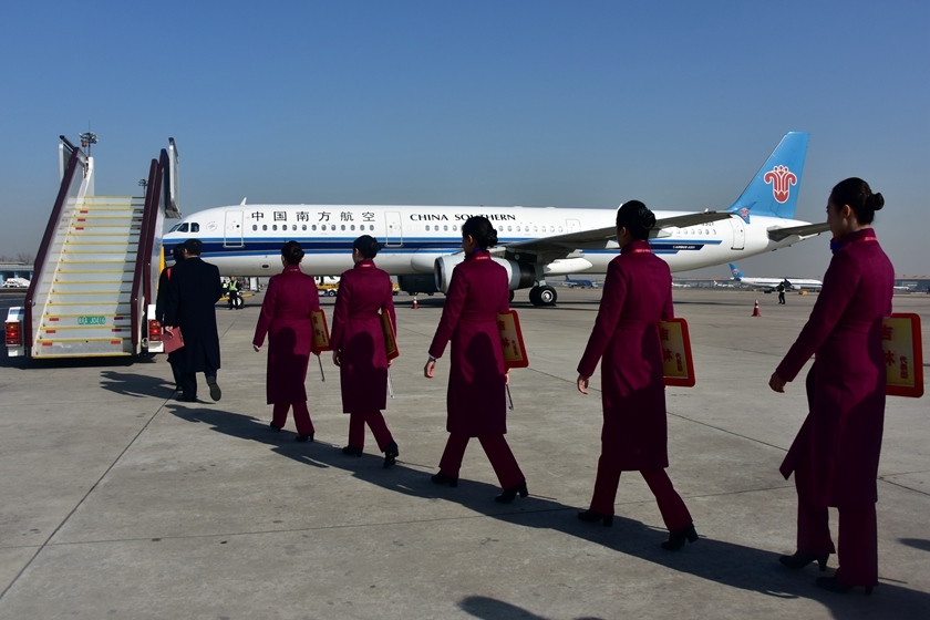 两会代表委员陆续抵京礼仪小姐举引导牌迎接