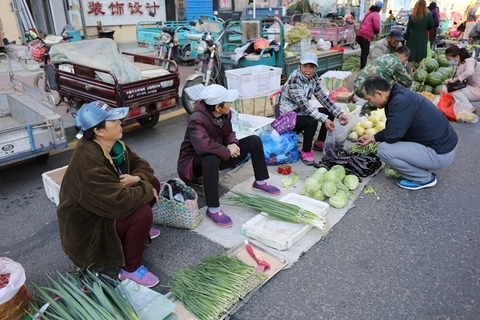 2017年7月25日，黑龙江黑河，连日来，受冷空气影响，黑龙江全省范围内出现大面积降温，由于最低气温低至12度，黑河市早起购物卖货的人们纷纷选择穿棉袄出行，穿着各式各样棉衣的菜农正在卖菜。图/视觉中国
