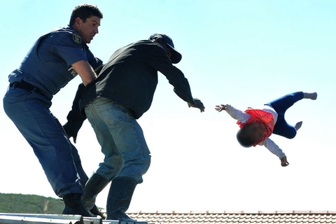 当地时间2018年4月12日，南非伊丽莎白港，南非一名男子为抵制政府拆除他所居住的非法建筑，将自己才六个月大的孩子从屋顶扔下。图/东方IC